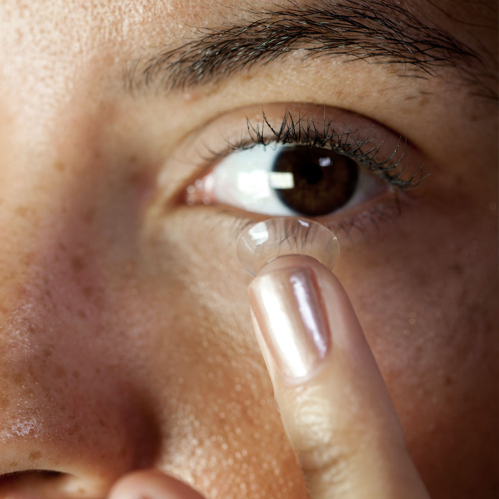 Close-up of a person putting a contact lens onto their eye Close-up of a person putting a contact lens onto their eye