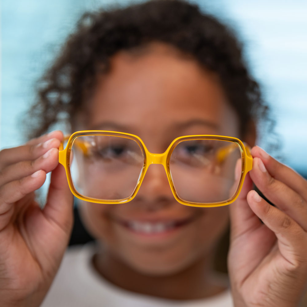 Girl holding a yellow frame to the camera Girl holding a yellow frame to the camera
