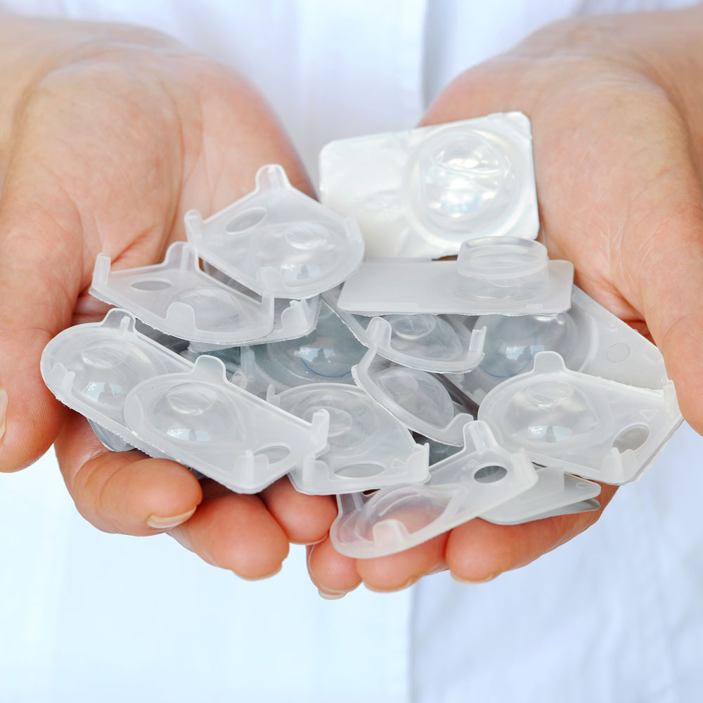 Close-up of hands holding several contact lens blister packs Close-up of hands holding several contact lens blister packs